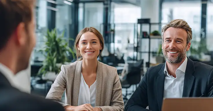 Lächelnde Frau und Mann bei Immobilienberatung im Büro