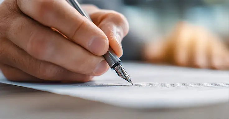 Hand mit Stift unterschreibt Dokument