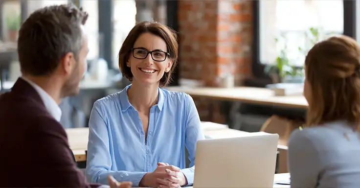 Lächelnde Frau bei Immobilienberatung mit zwei Personen